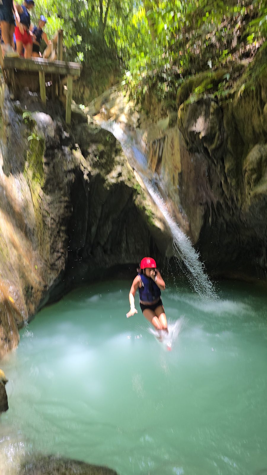 Visitante saltando a una poza de agua turquesa durante la excursión 7 Waterfalls